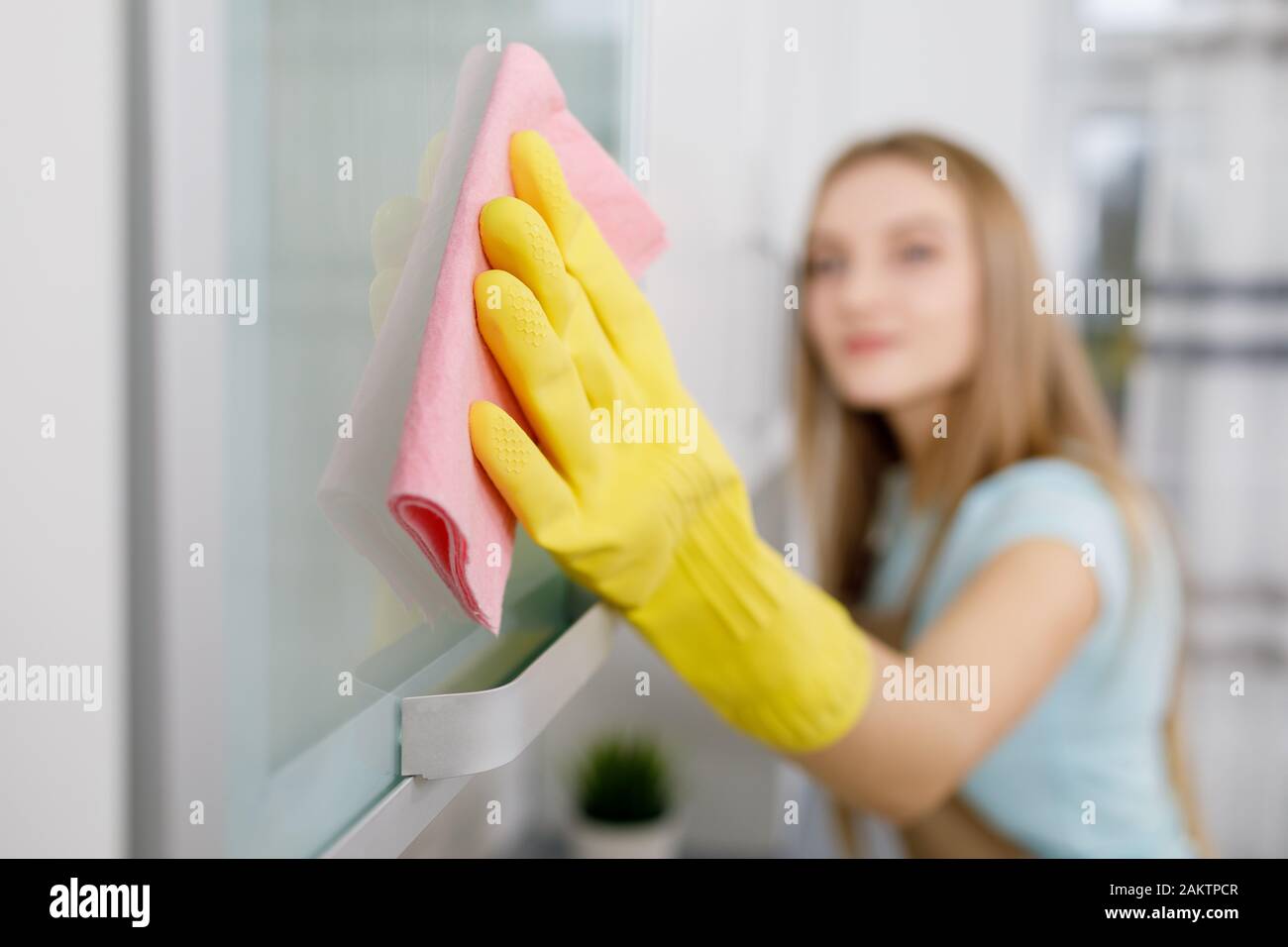 Gros plan de la jeune femme blonde dans un placard à laver avec des gants jaunes Banque D'Images