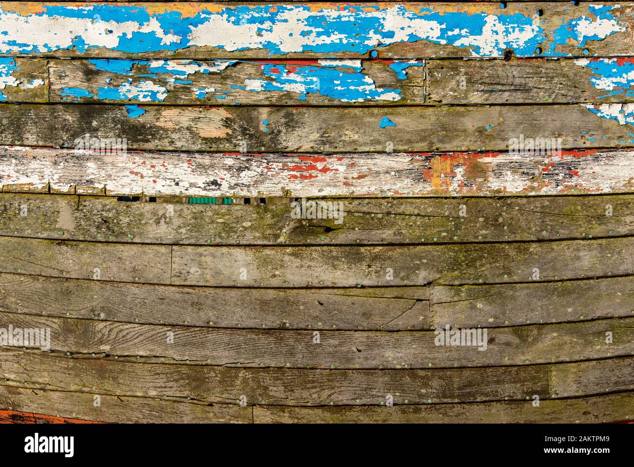 Abstraite de la côté d'un bateau de pêche en bois montrant de nombreuses couches de peinture altérée. Banque D'Images