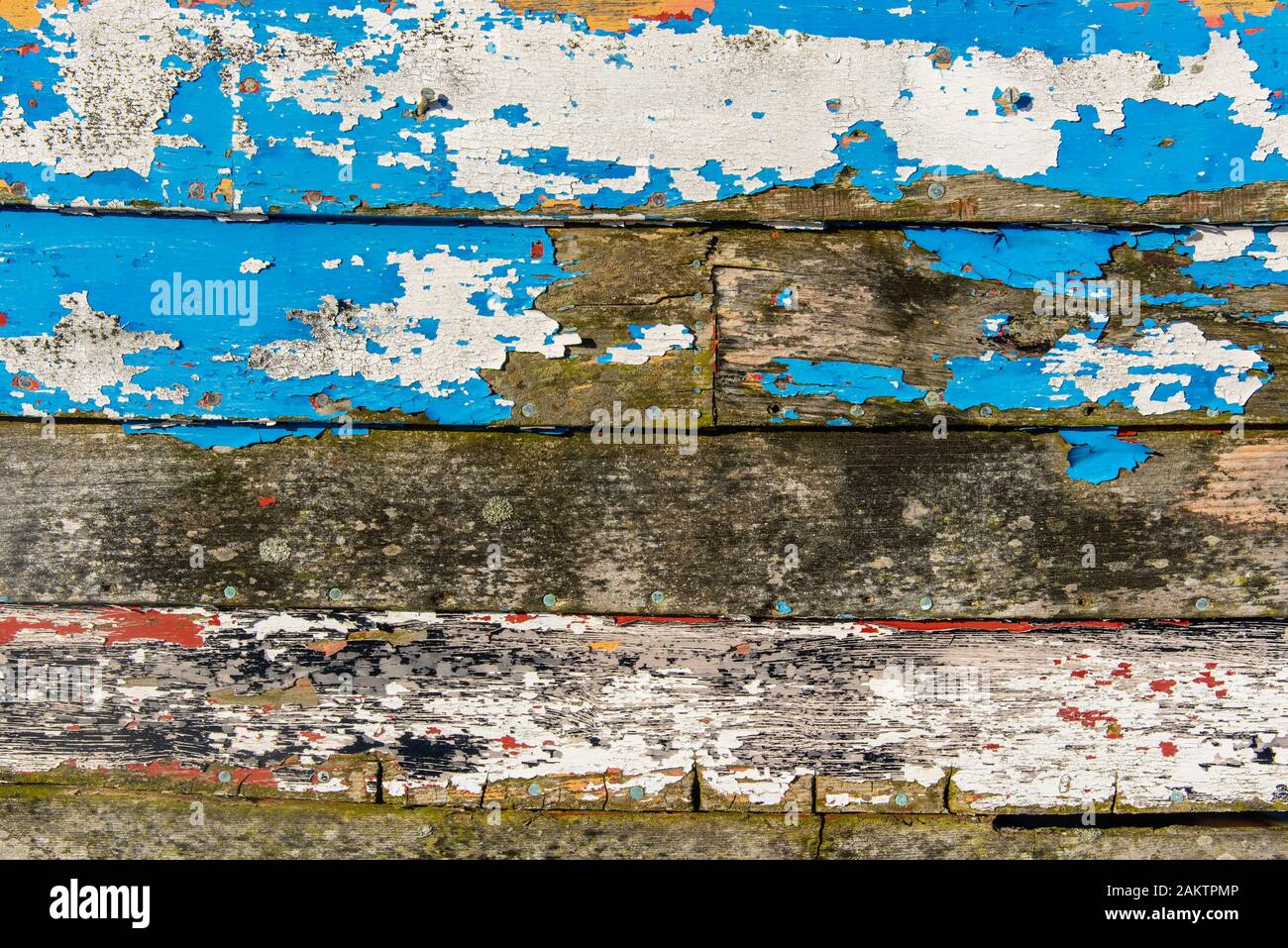 Abstraite de la côté d'un bateau de pêche en bois montrant de nombreuses couches de peinture altérée. Banque D'Images