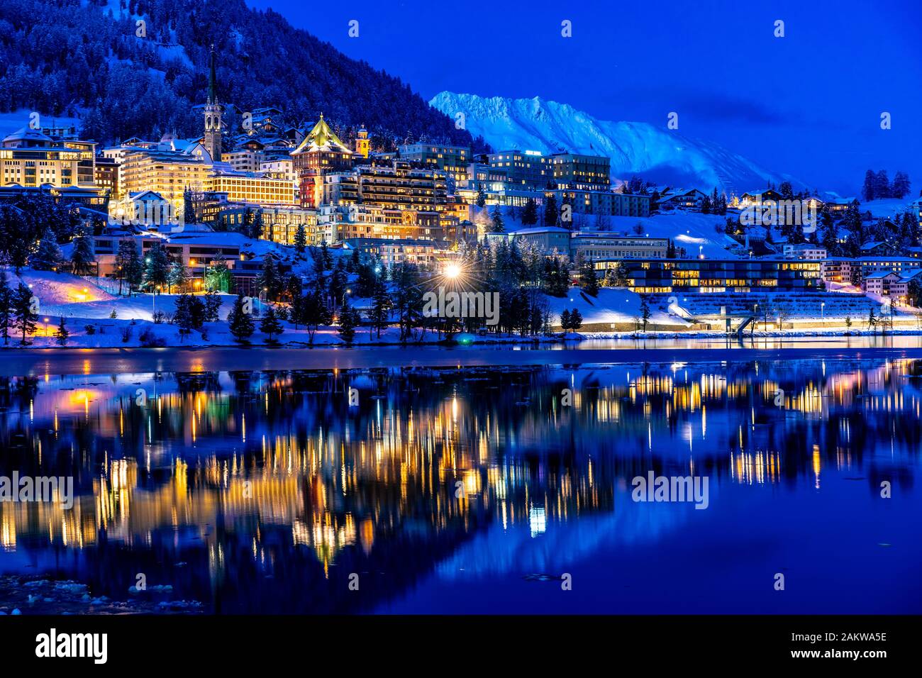 Vue sur les magnifiques lumières nocturnes de Saint-Moritz en Suisse la nuit en hiver, avec réflexion du lac et des montagnes de neige dans le backgrouind Banque D'Images