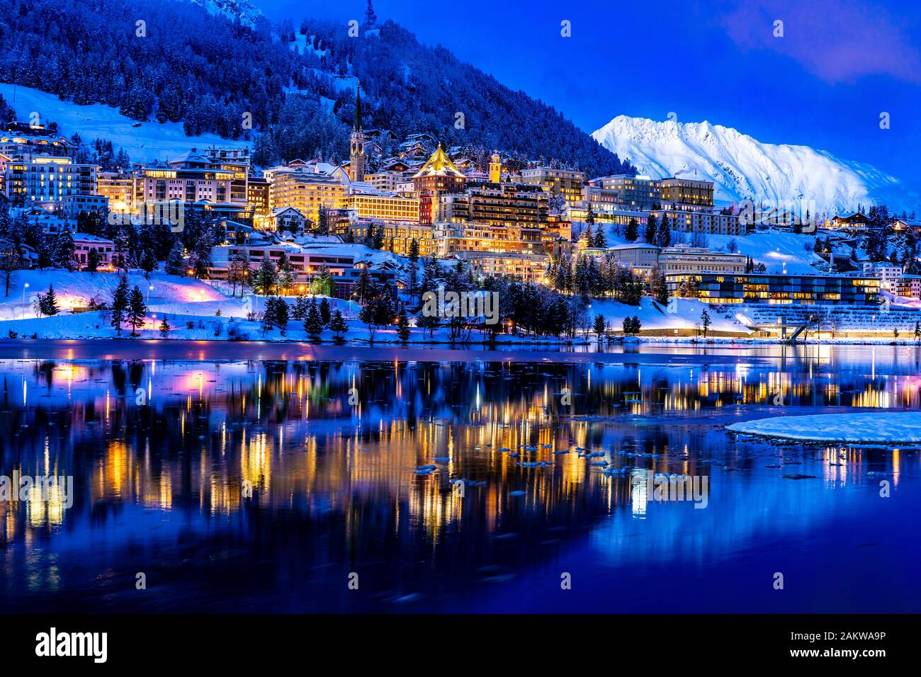 Vue de belles lumières nocturnes de Saint-Moritz en Suisse la nuit, avec réflexion du lac et des montagnes de neige dans l'arrière-plan Banque D'Images