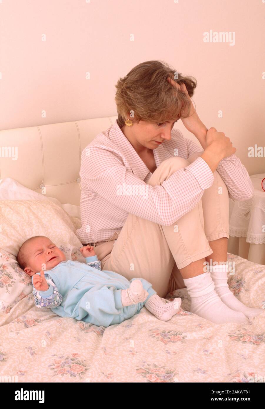 jeune mère avec un bébé souffrant de dépression postnatale, regardant triste, assis sur un lit Banque D'Images