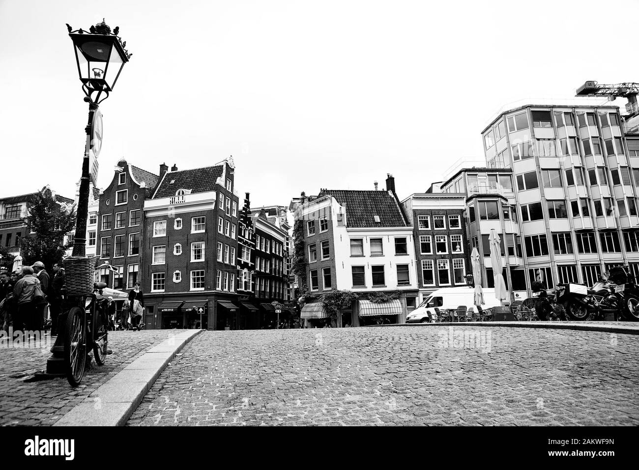 Image en noir et blanc de la route pavée sur le pont d'Amsterdam avec vélo attaché à l'ancien lampadaire Banque D'Images