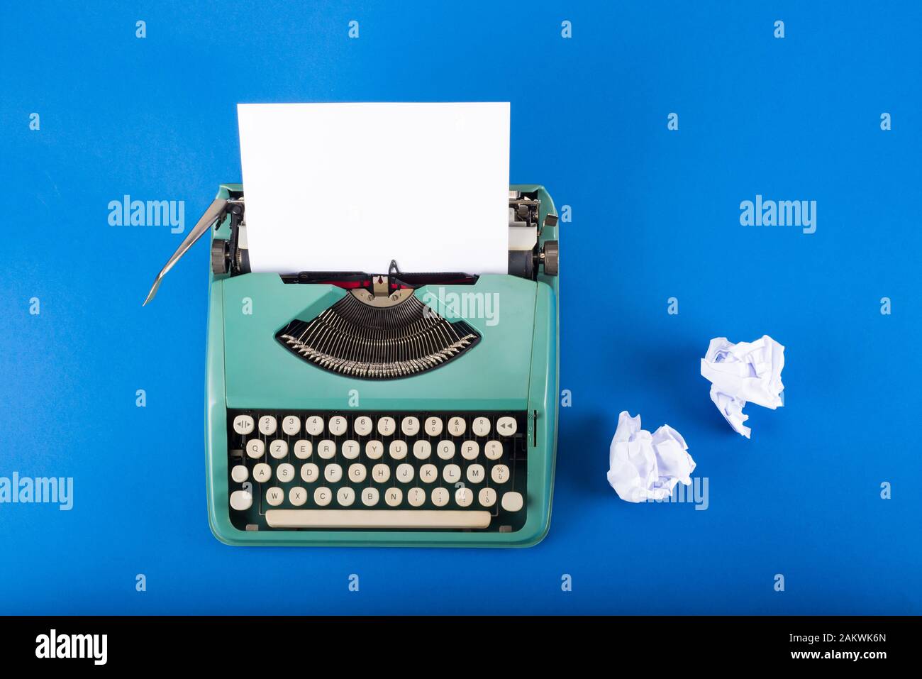 Machine à écrire vintage et papiers froissés sur fond bleu avec espace de copie Banque D'Images