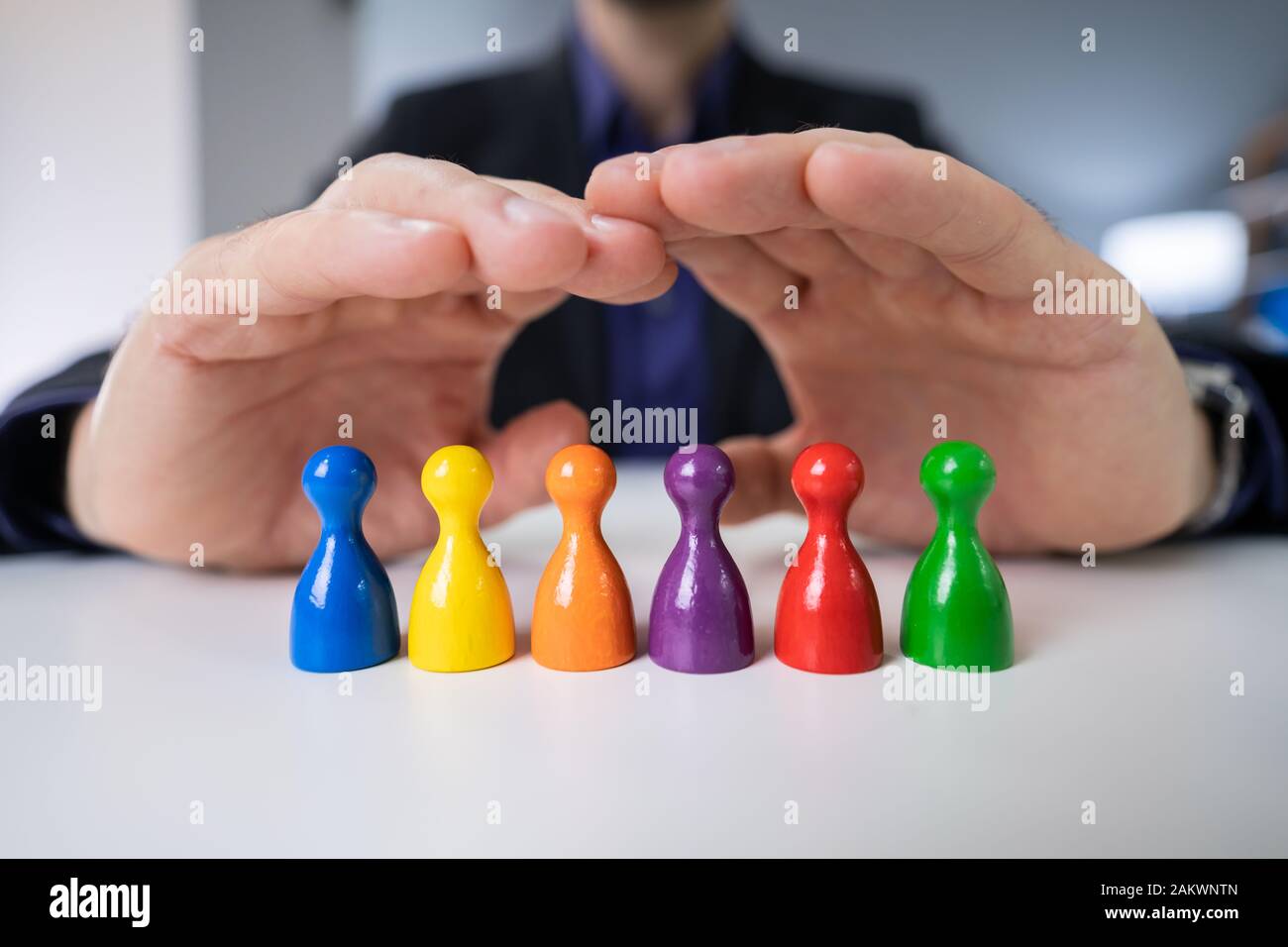 La main de la personne la protection des pions multicolores sur blanc 24 Banque D'Images