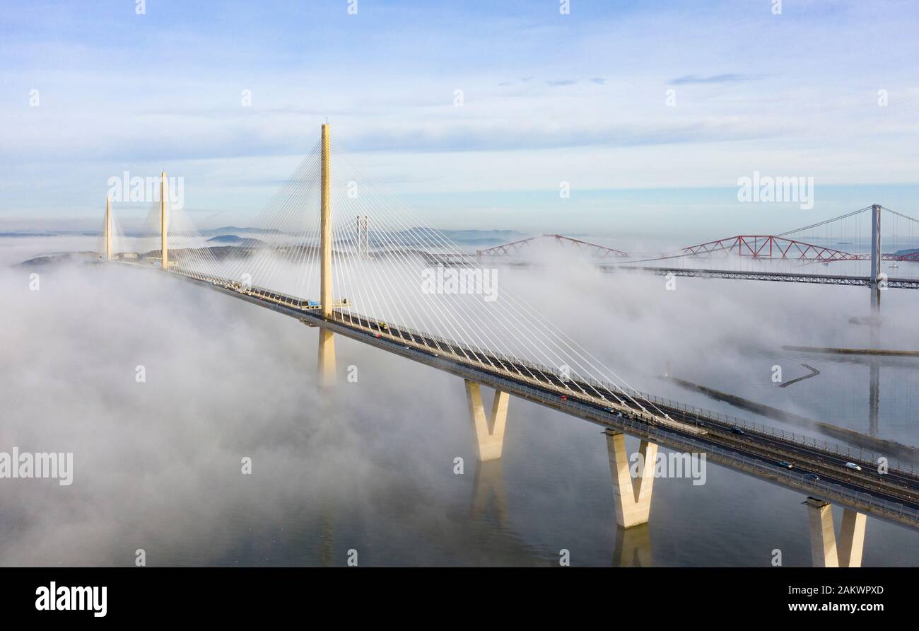 South Queensferry, Ecosse, Royaume-Uni. 10 janvier 2020. Drone image d'un nuage à l'inversion spectaculaire Queensferry Crossing Bridge avec la moitié inférieure du pont enveloppé dans le brouillard, mais la moitié supérieure dans un beau temps ensoleillé. En arrière-plan le pont du Forth et Forth Road Bridge. Iain Masterton/Alamy Live News Banque D'Images