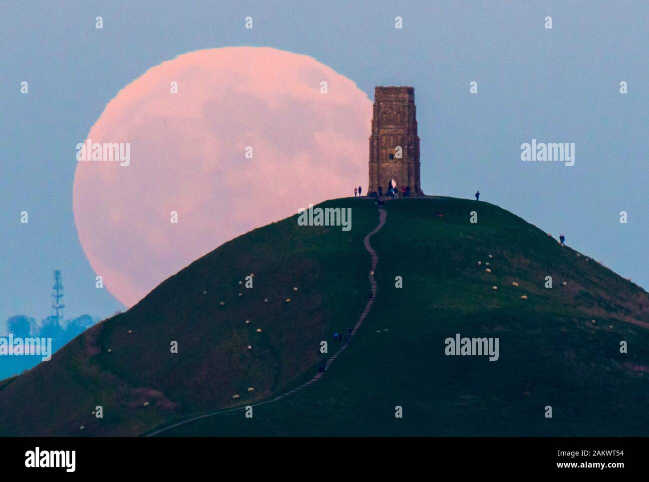 Glastonbury, Somerset, Royaume-Uni. 10 janvier 2020. Météo britannique. Le loup pleine lune se lève derrière Tor de Glastonbury dans le Somerset sur une bonne soirée d'hiver où les visiteurs se sont réunis pour regarder le lever de la lune au coucher du soleil. Crédit photo : Graham Hunt/Alamy Live News Banque D'Images