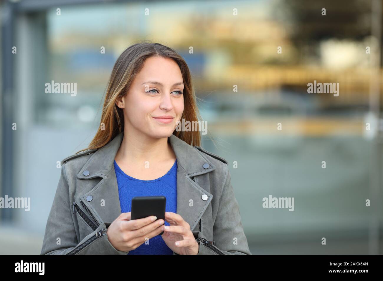 Vue avant portrait of a woman holding mobile phone à côté de dans la rue Banque D'Images