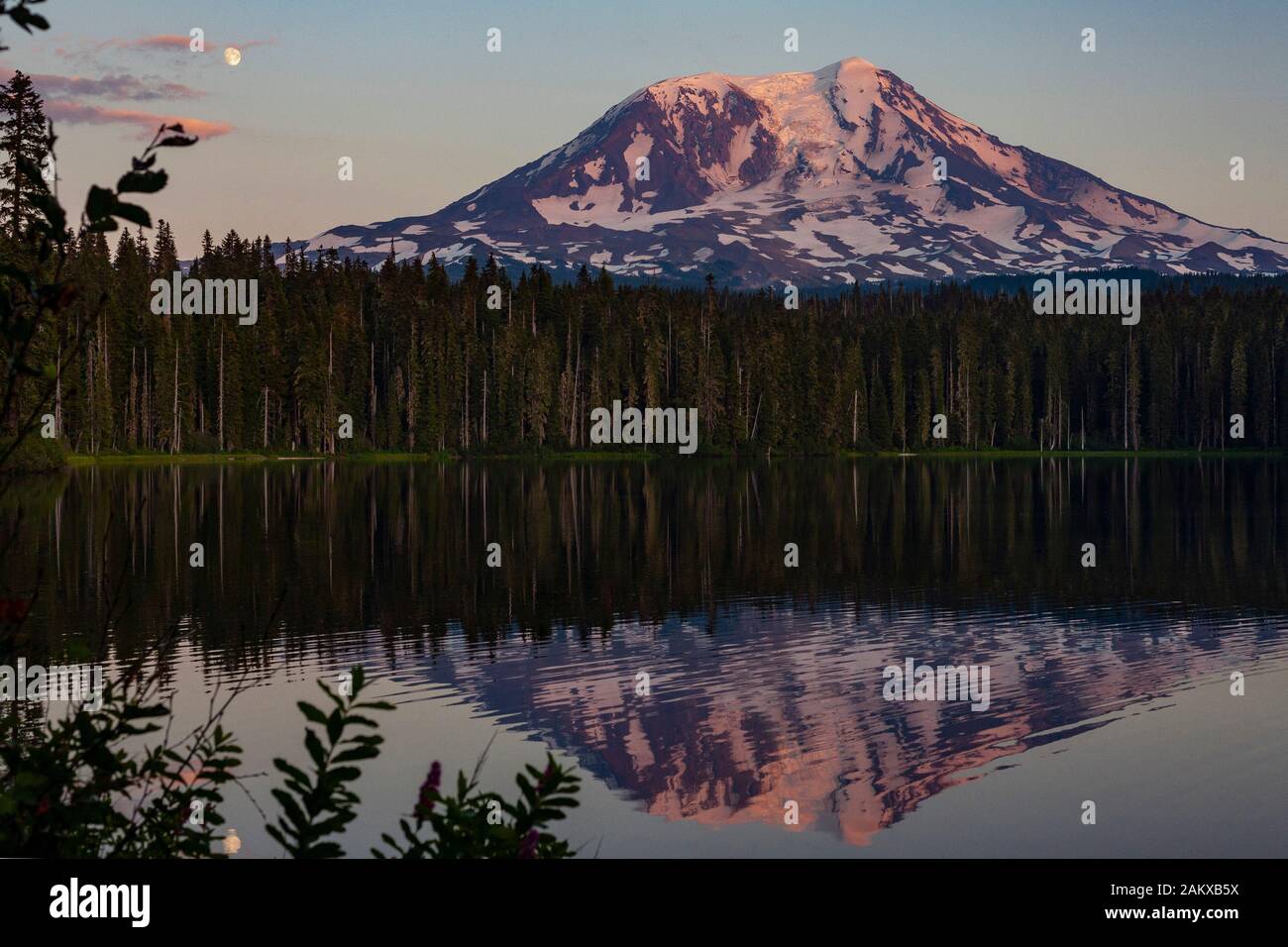 La lune s'élève sur le mont Adams et une réflexion est vue dans le paisible lac de Takhlakh. Le coucher du soleil couleur la montagne et le ciel. Banque D'Images