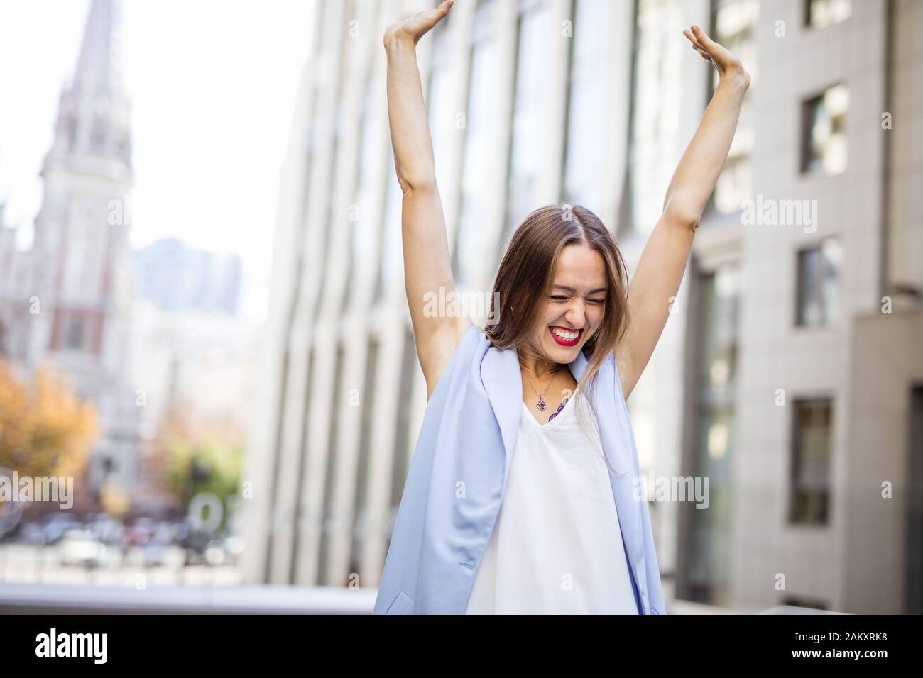 Heureuse jeune femme levant les bras dans le centre-ville de joie le jour d'automne Banque D'Images