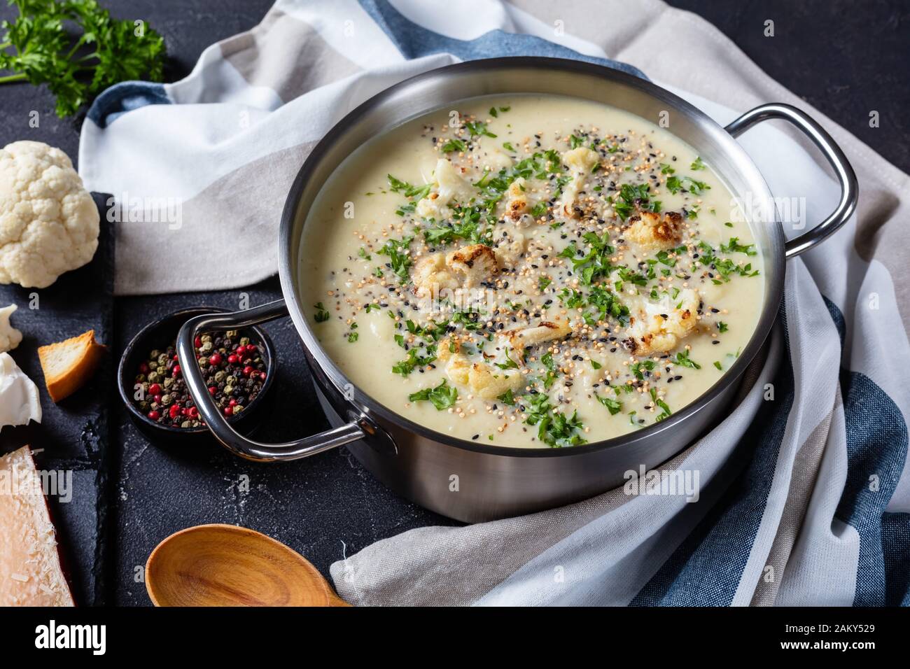 Gros plan de la soupe de Chou-Fleur à l'ail rôtie d'Asiago dans un marmite avec ingrédients et croûtons sur une table en béton, vue horizontale d'en haut Banque D'Images