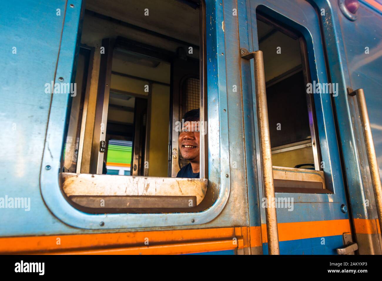 Bangkok/Thaïlande-décembre 2019: Un chef de train assis et souriant à la caméra dans son vieux train bleu à la gare de Hua Lamphong. Banque D'Images