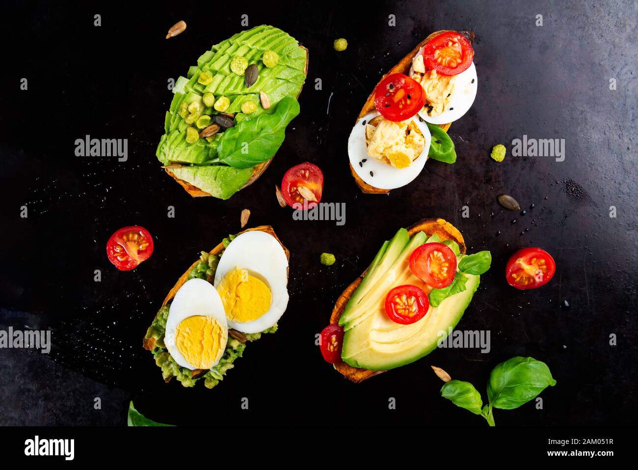 Toasts de patate douce avec avocat, œufs durs, tomates et graines de sésame sur fond sombre. Concept de repas sain. Cuisine propre, plats du Pescetarian, vue sur le dessus Banque D'Images