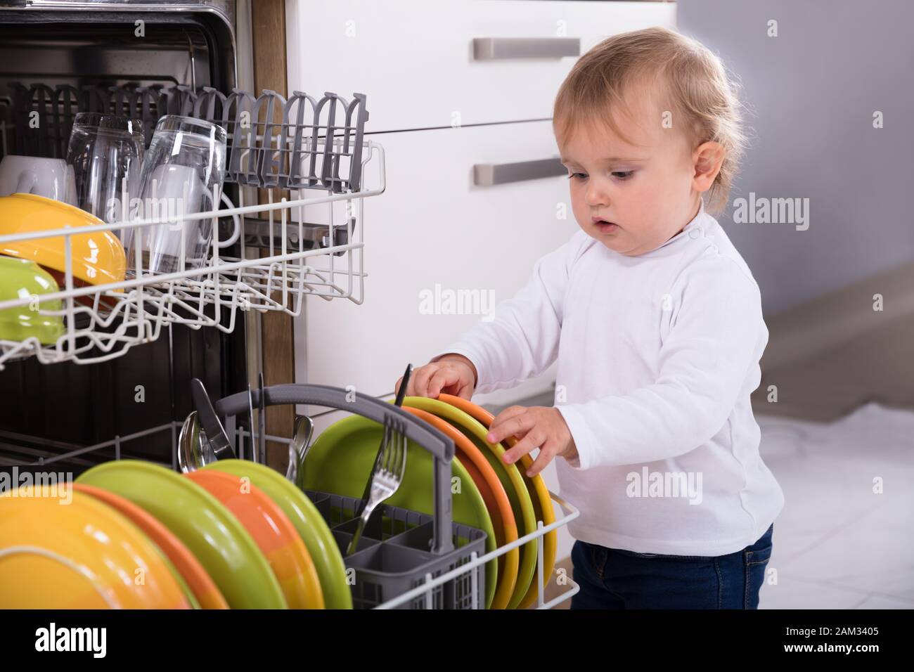Petite fille le déchargement d'un lave-vaisselle dans la cuisine à la maison Banque D'Images