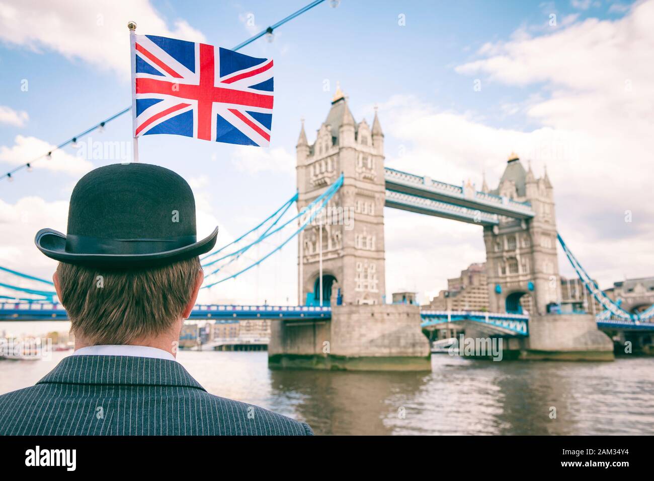 Méconnaissable d'affaires britannique en noir chapeau melon avec Union Jack flag debout devant le Tower Bridge, Londres Banque D'Images