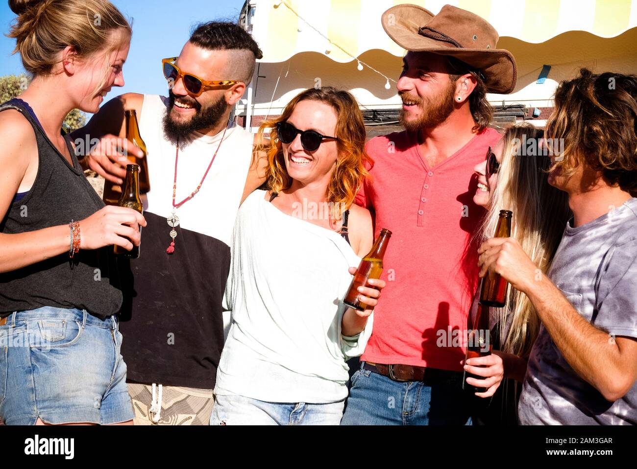 Groupe de jeunes caucasiens alternatifs ont plaisir et profiter avec l'amitié et les sourires et bouteilles de bière - le style de vie jeune pour différents Banque D'Images