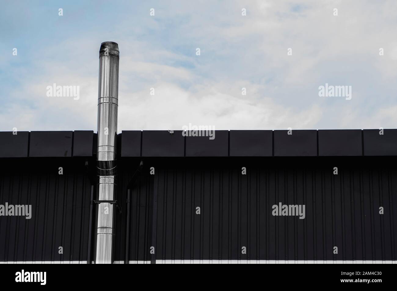 Noir et blanc surface texture feuille de métal ondulé sur la paroi d'un immeuble avec un ciel nuageux. Fond en acier galvaniser. Banque D'Images