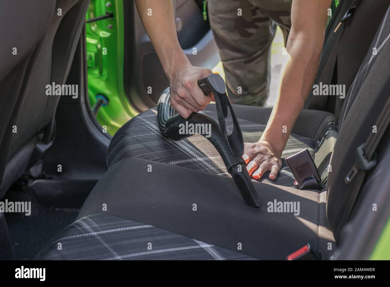 Les mains du jeune homme de l'intérieur nettoyage voiture à l'aide d'aspirateur Banque D'Images