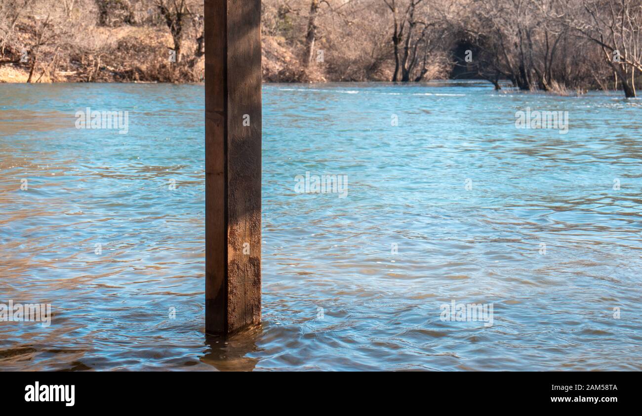 Poutre en bois debout dans l'eau, zone inondée du niveau d'eau de la rivière en hausse. Fonte de neige Banque D'Images