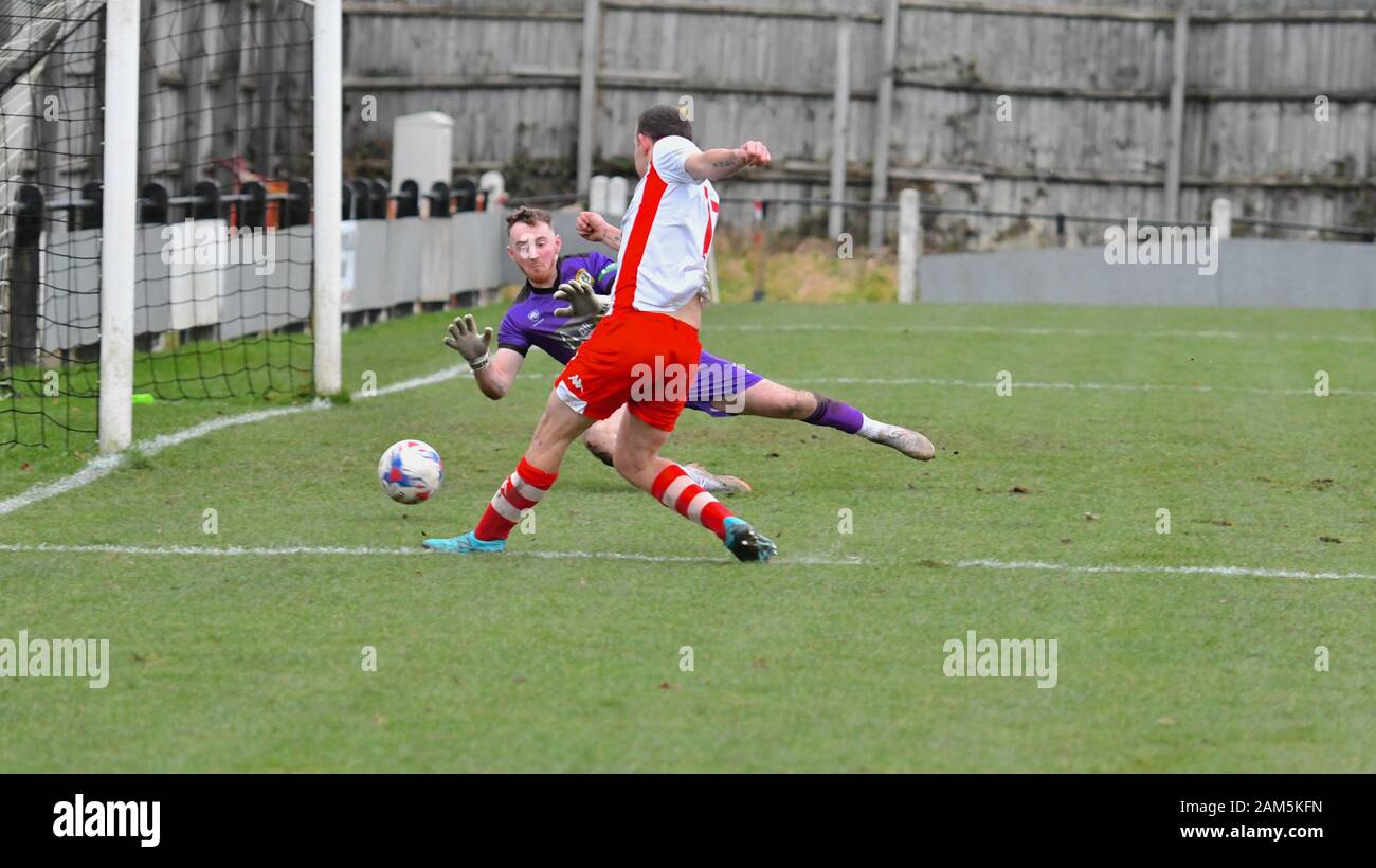 Les nouvelles usines v Cheadle Ville 11 Janvier 2020 Un joueur lance Cheadle dans le filet latéral. Action de la Ligue Nord-ouest de comtés correspondre. Les nouvelles usines en jaune et noir et Cheadle ville en rouge et blanc. La ville de Cheadle gagner 2-1. Banque D'Images