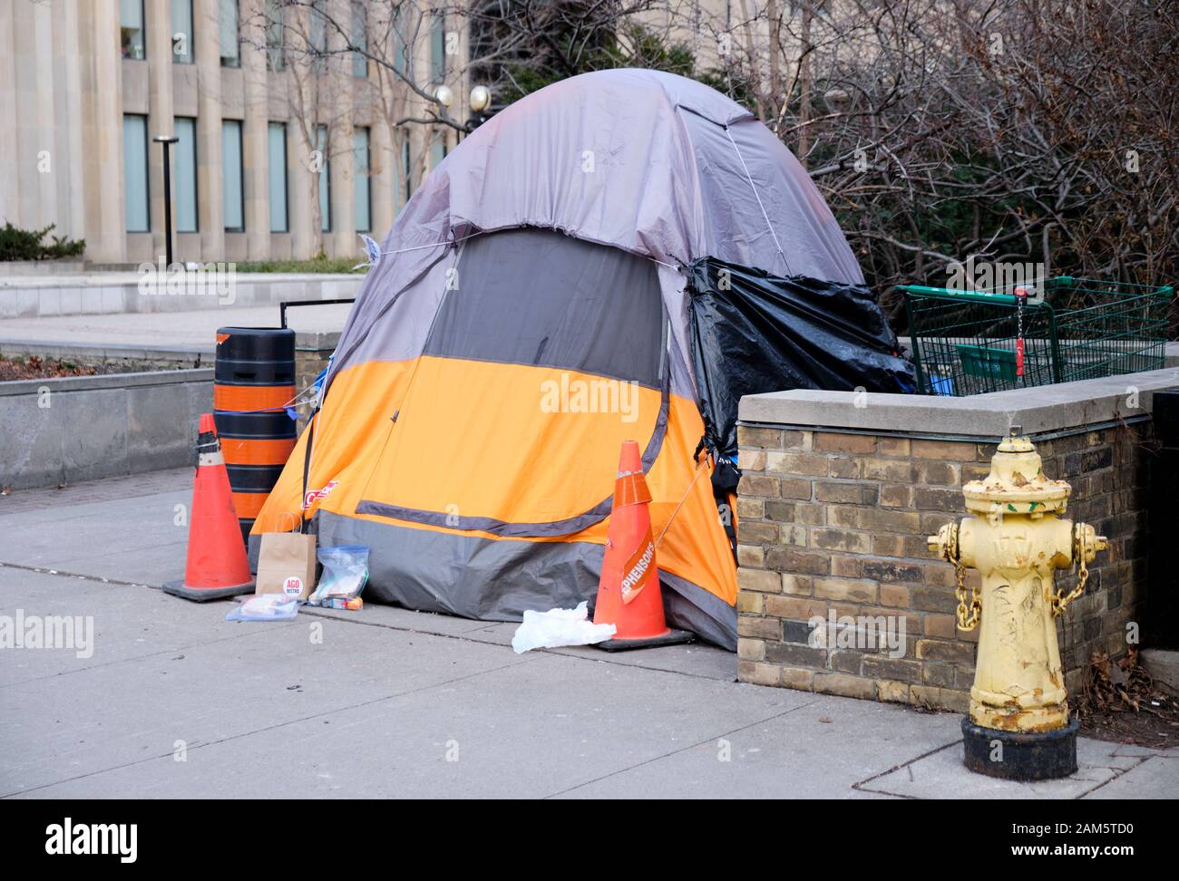 Les sans-abri tente montée sur le trottoir de l'avenue University, dans le  centre de Toronto, lors d'une froide journée d'hiver, gris. Habitant établi  leur camp avec panier alimentaire sur s Photo Stock -