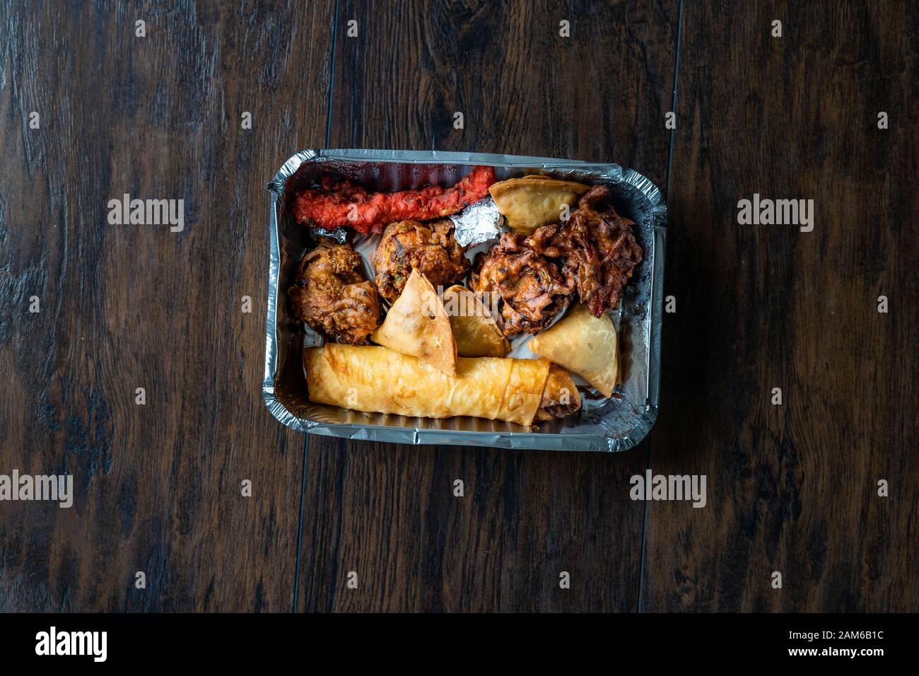 Enlever la plaque avec la nourriture indienne Pakora Poulet, Aloo Tikki, Samosas Samsa et des rouleaux de printemps dans un contenant de plastique fort / paquet. La nourriture traditionnelle. Banque D'Images