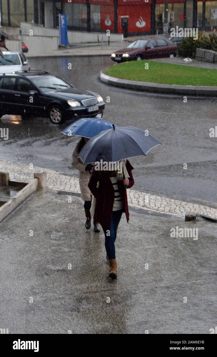 Les piétons essaient de rester au sec sous de fortes pluies à Coimbra Portugal Banque D'Images