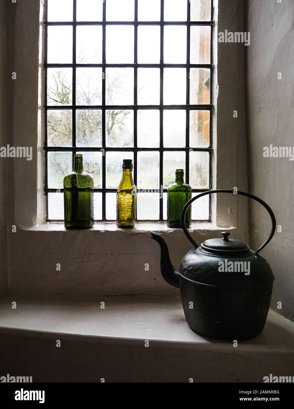 Bouteilles de gin vides colorées et une bouilloire à l'ancienne sur un rebord de fenêtre dans une ancienne auberge anglaise de coaching dans Les Cotswolds. Banque D'Images