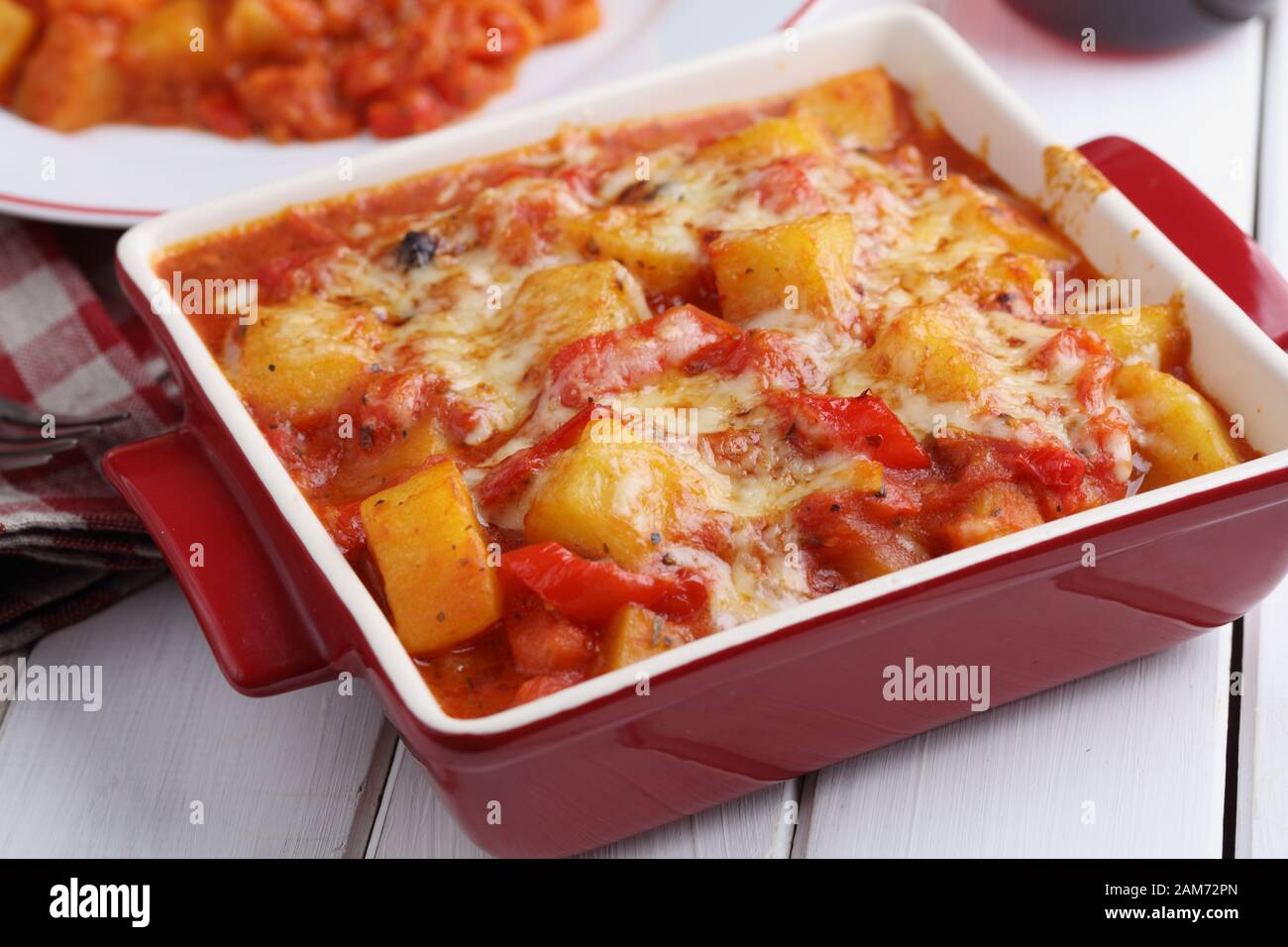 Ragoût végétarien avec pomme de terre, poivron, carotte, et le fromage râpé dans un plat allant au four, sur une table rustique Banque D'Images