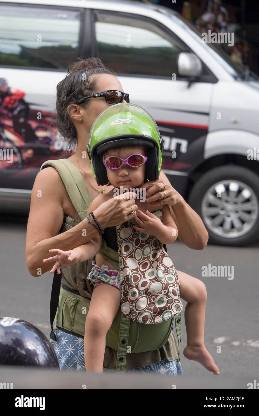 Jeune mère touristique plaçant un casque de scooter vert citron sur son  verre de soleil rose portant une jolie petite fille avant de monter sur le  scooter Photo Stock - Alamy