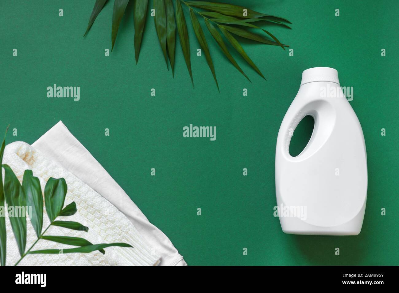 Lessive écologique en flacon en plastique blanc avec feuilles vertes sur fond vert, vue de dessus, espace de copie. Produit de nettoyage éco-recyclage, éco-protection Banque D'Images