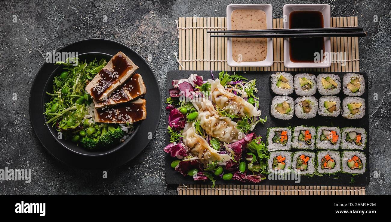 Bannière alimentaire. Petits pains à sushi avec légumes, boulettes, salades. Cuisine chinoise sur fond gris en béton. Cuisine asiatique. Vue de dessus Banque D'Images