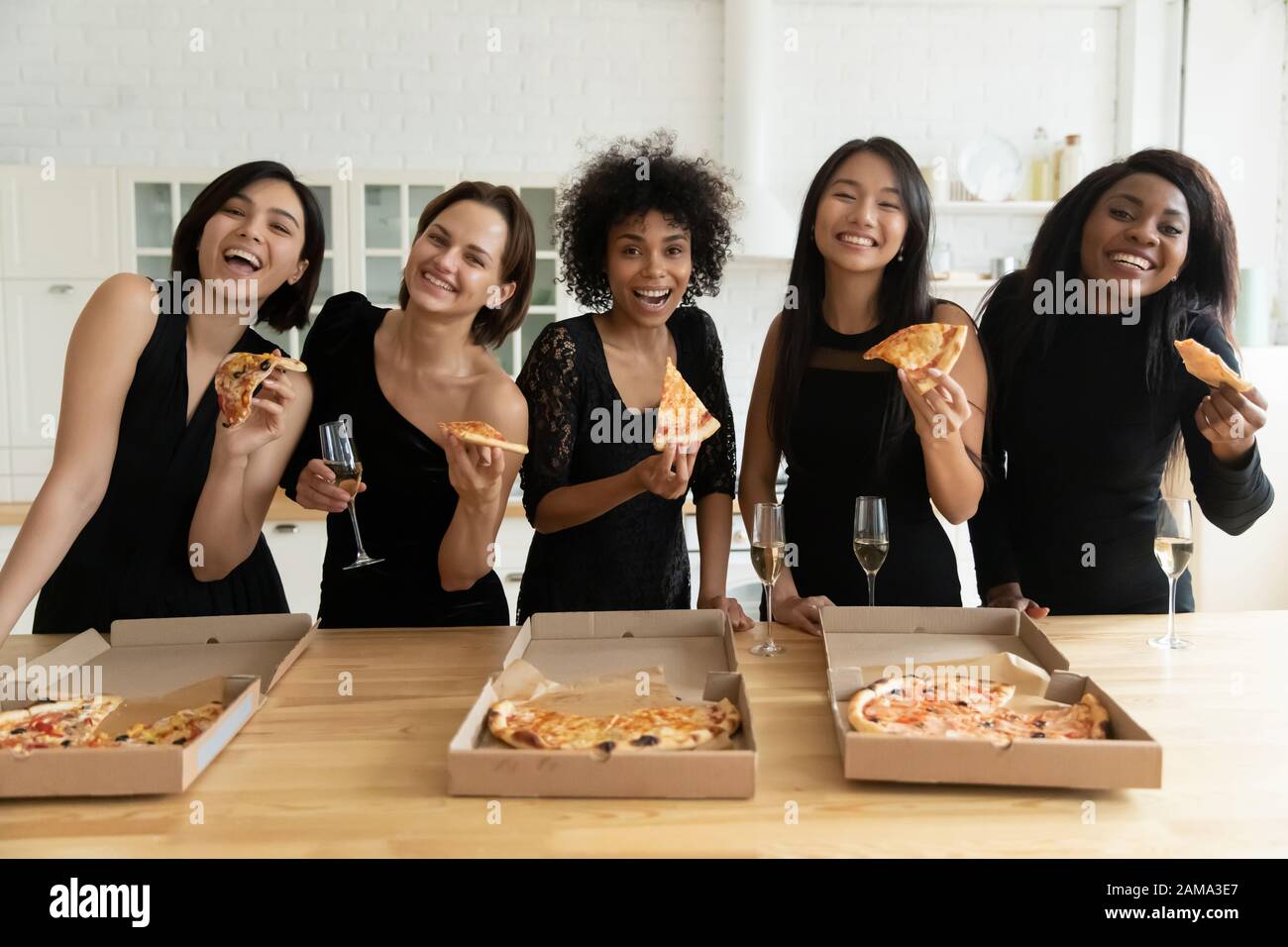 Des filles souriantes et diverses mangent de la pizza pour fêter la fête des jeunes filles à la maison Banque D'Images