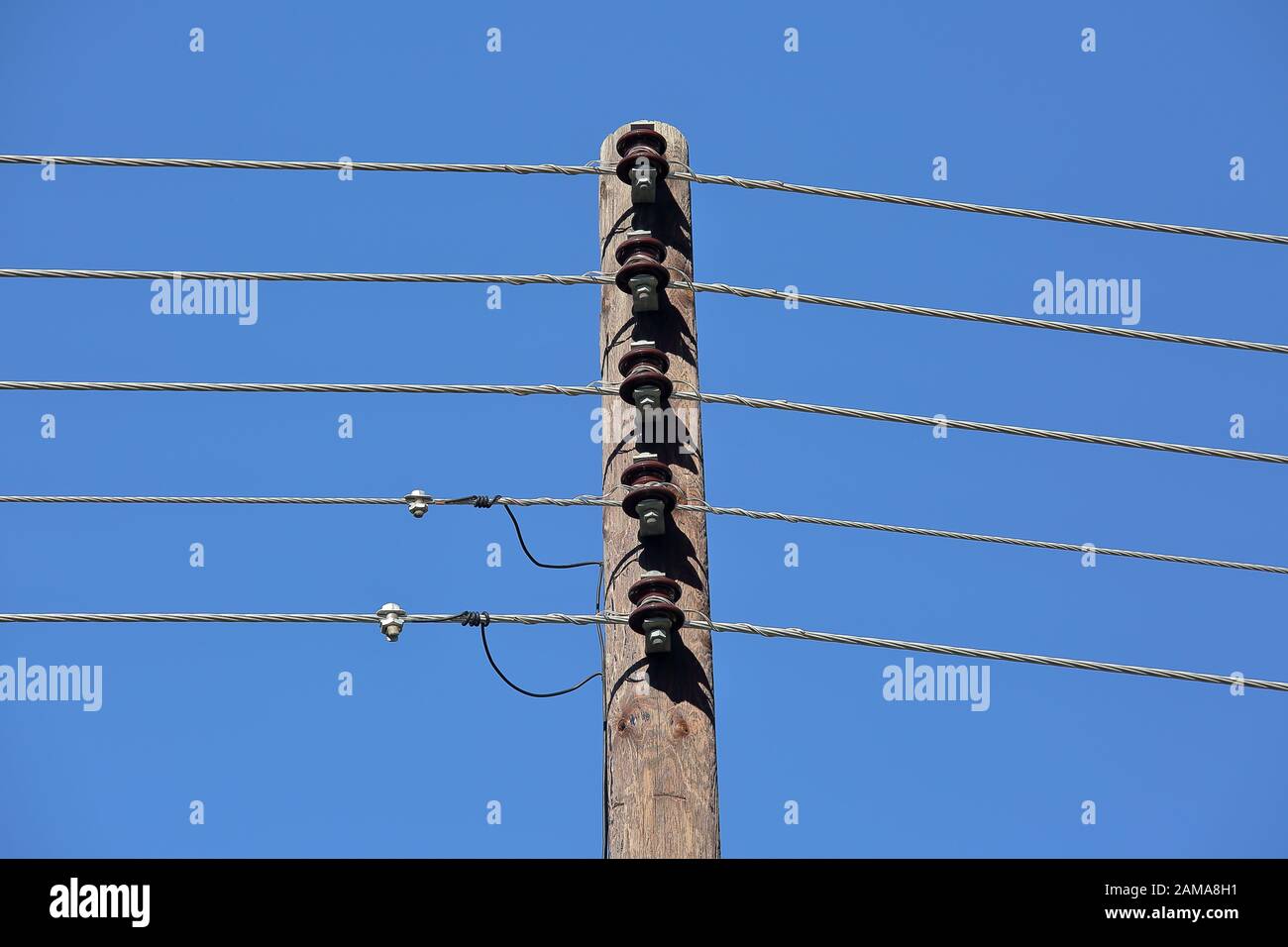 Poteau en bois avec des fils électrique / câbles close up against blue sky Banque D'Images