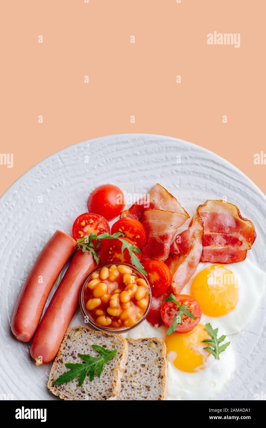 Petit déjeuner copieux : œufs frits, pain, saucisses, bacon, tomates cerises et haricots. Banque D'Images