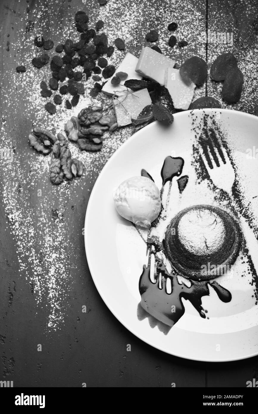 Gâteau de lave fondu français avec silhouette de fourche sur la plaque. Concept de pâtisserie. Fondant au chocolat avec crème glacée et sauce au chocolat sur fond gris. Dessert servi avec des fruits secs dans un café ou une boulangerie. Banque D'Images