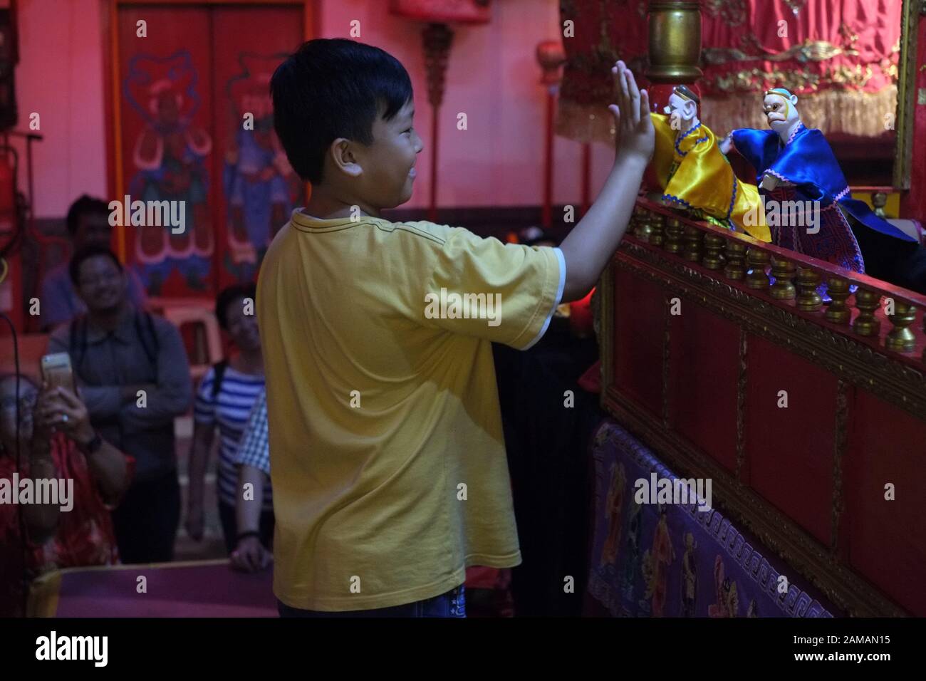 Un garçon essaie de secouer la main d'une marionnette traditionnelle chinoise. Banque D'Images