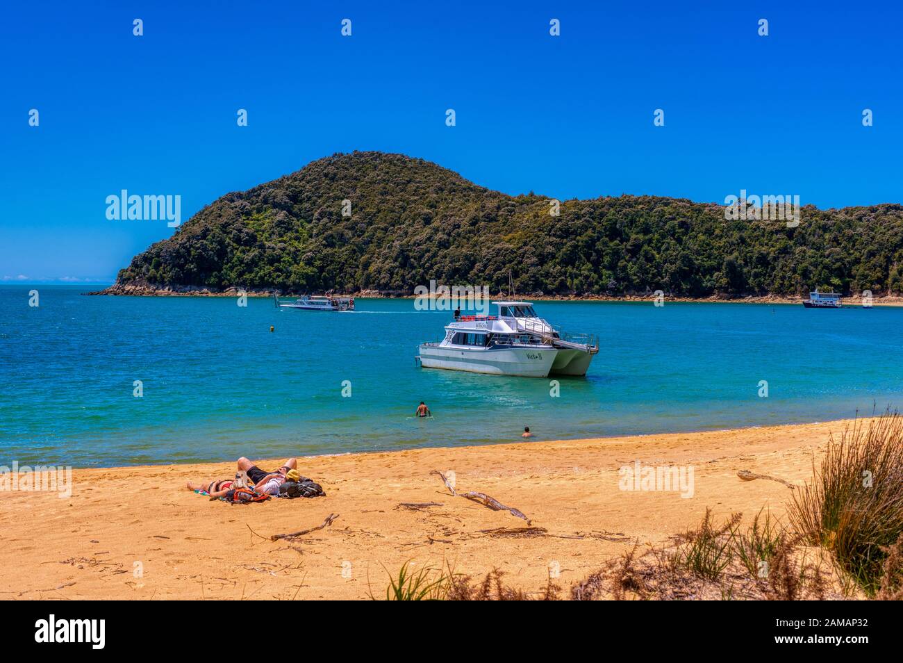 Relaxing sur la plage près d'un bateau-taxi au parc national d'Abel Tasman, Nouvelle-Zélande Banque D'Images