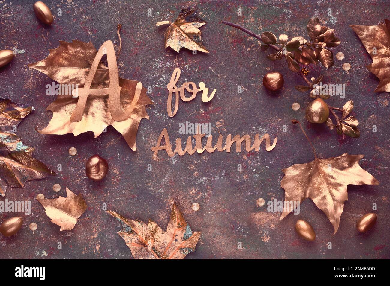 Plat d'automne, vue de dessus avec feuilles dorées peintes et texte « A for Autumn » sur fond brun foncé texturé. Bonne automne pour tous ! Banque D'Images