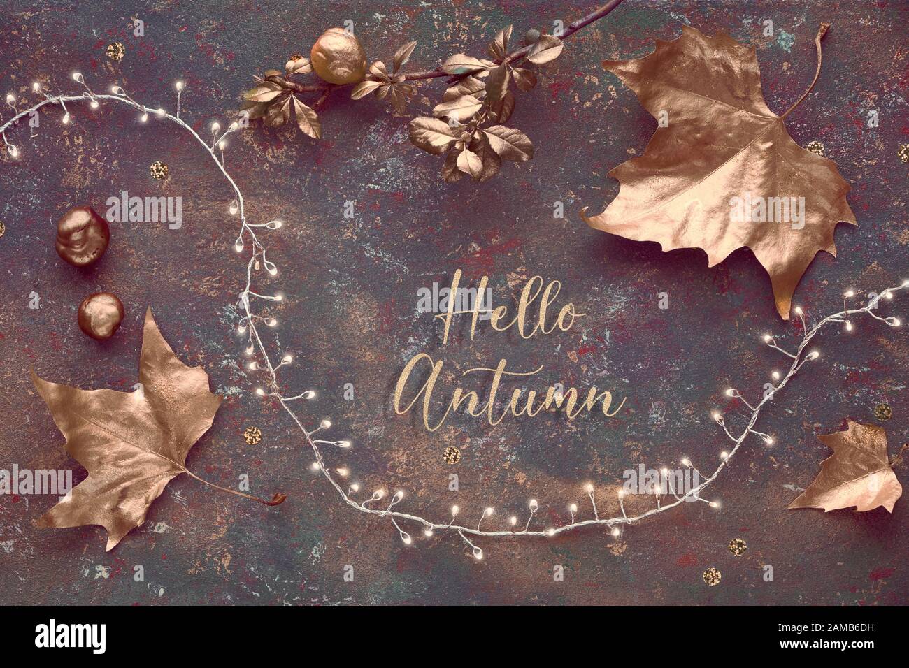 Automne, coupond panoramique créatif. Vue de dessus des feuilles dorées peintes, guirlande lumineuse festive sur fond vert foncé texturé. Texte « Bonjour Automne » I Banque D'Images