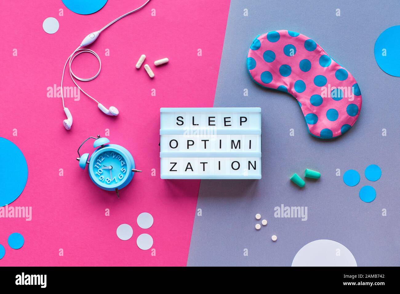 Texte « optimisation du sommeil » sur la visionneuse. Masque de sommeil en points polka, réveil, écouteurs, bouchons d'oreilles, capsules avec remède au sommeil. Plat, vue de dessus, Banque D'Images