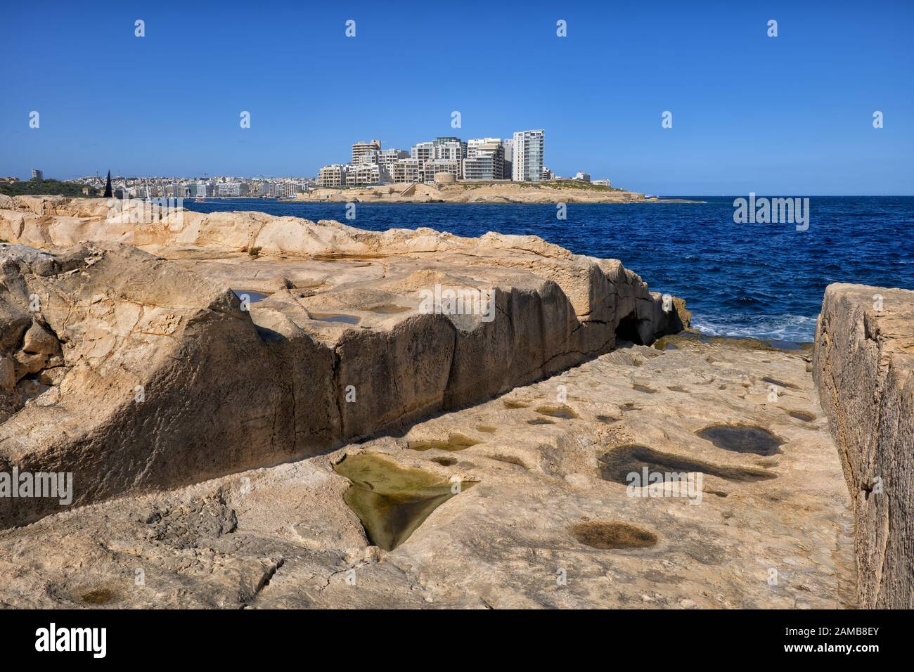 Valette bord de mer à Malte, cale (rampe ou lancement de bateau, déployeur de bateau) à la mer sculpté dans la rive rocheuse avec la ville de Sliema à l'horizon Banque D'Images