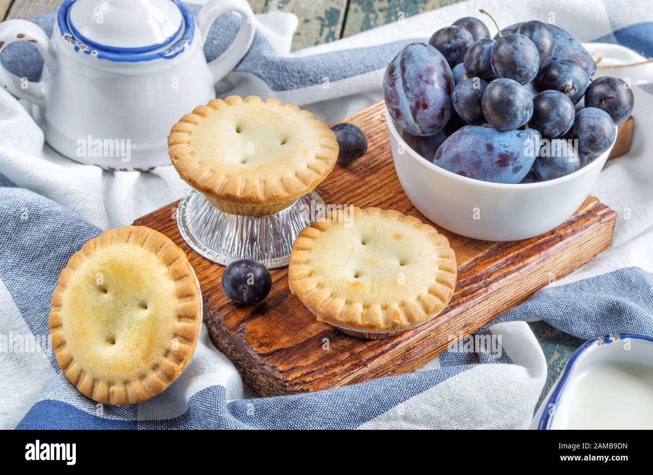 Trois petits gâteaux clos avec prunes et un crémier et bol à sucre dans un style vintage Banque D'Images