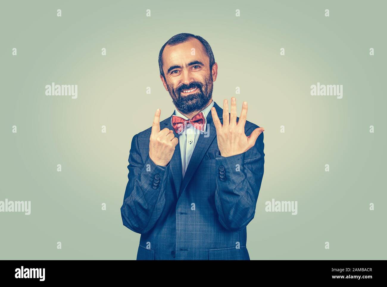 Portrait souriant, homme barbu heureux montrant 6 doigts, donnant le signe numéro six, le sixième isolé sur fond vert jaune. Émotion humaine positive f Banque D'Images