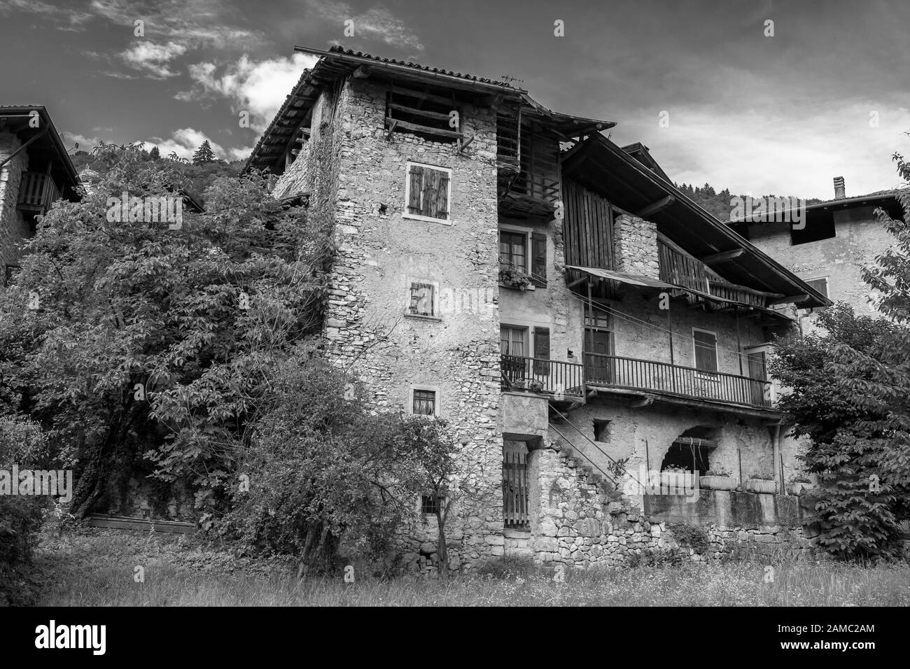 De grandes maisons anciennes avec balcon dans le village médiéval de Canale di Tenno, Trentin-Haut-Adige, Italie. Version noir et blanc Banque D'Images