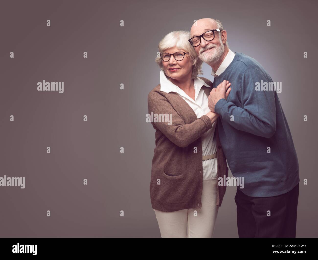 Portrait d'un couple senior doux embrassant , vêtements décontractés, fond gris Banque D'Images