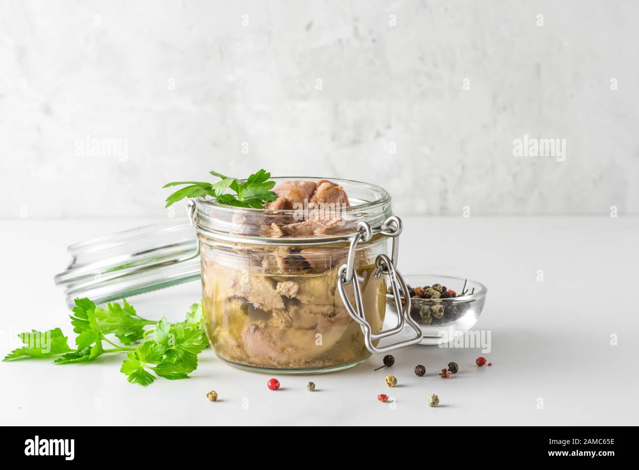 Foie de morue dans un pot avec persil et poivre sur fond blanc. Source naturelle d'oméga 3 et de vitamine D. proche de l'espace de copie Banque D'Images