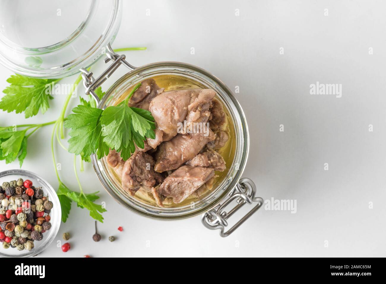 Foie de morue dans un pot avec persil et poivre sur fond blanc. Source naturelle d'oméga 3 et de vitamine D. vue de dessus avec espace de copie Banque D'Images