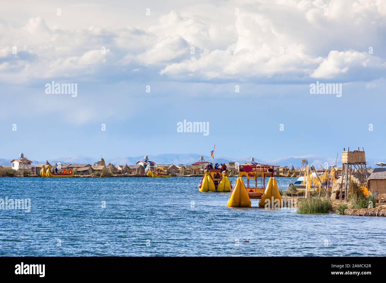 Îles Flottantes D'Uros, Lac Titicaca, Pérou, Amérique Du Sud - 2019-12-01. Vue sur l'île, un bateau des roseaux, ciel bleu dans les nuages. Banque D'Images