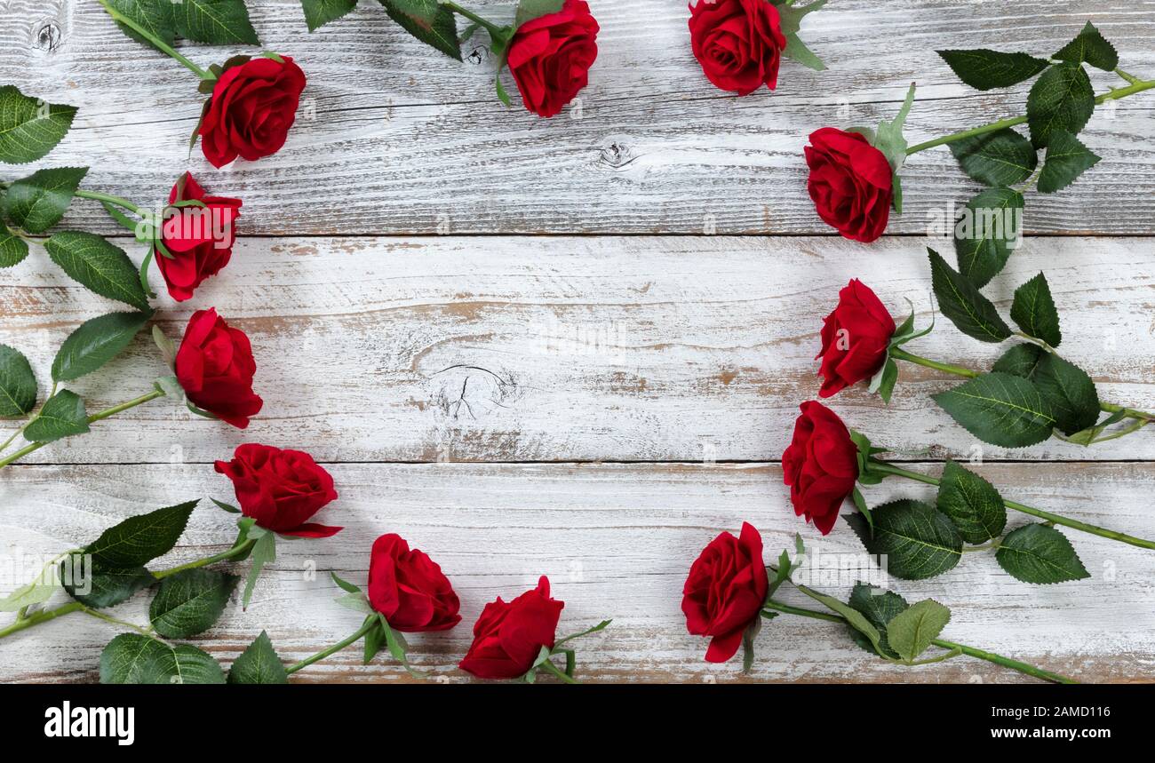 Bonne Saint Valentin avec des roses rouges formant des contours de coeur sur le bois rustique blanc Banque D'Images